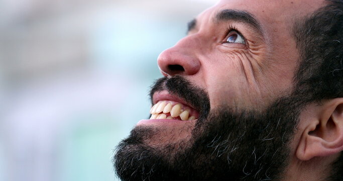 Hopeful man in 40s opening eyes to sky with FAITH, close-up face eye open