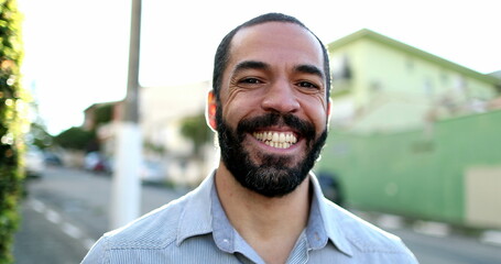 Hispanic man smiling at camera standing outside in street. South American person portrait smile