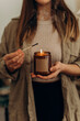 a burning candle in a jar close-up in the hands of a young beautiful woman. the girl lit a candle in her hands.
