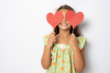 Wall Mural - Happy girl with two carton paper small little heart figures standing isolated over white background. Love concept.