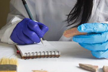 Curator and archaeologist taking notes and describing a pottery shard found in an archaeological find