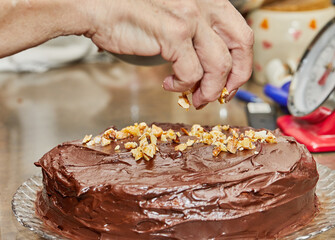 Poster - Chef sprinkles walnuts on the cake to make chocolate cake with pears and walnuts