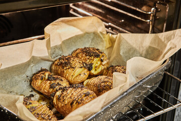 Poster - Baked Hasselback Hedgehog Potato with Provence Herbs in the oven after baking. French gourmet cuisine