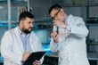 © kuzovkov - Male scientist with a large flask in his hands. He examines some liquid in a test tube. Working in a scientific laboratory.