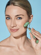 © Peakstock - Face jade roller. Face of beautiful woman with green jade roller for anti-aging procedures
