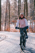 A woman rides a bike in winter. Concept of cycling during snowy weather. Snow and sun weather in the park