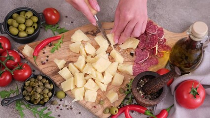 Canvas Print - Woman chopping parmesan cheese piece with knife on wooden board at domestic kitchen 