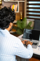 vertical shoulder shot of IT employee coding on laptop at office - conept of software developer, while collar jobs and expert