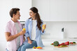 Beautiful smiling healthy couple in love with juice in their hands in the kitchen, vegetarian nutrition.