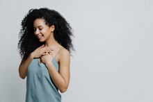 Profile Of Dreamy Romantic Ethnic Woman With Afro Haircut, Dressed In Nightwear, Keeps Hands On Chest, Recalls Very Pleasant Moment In Life Smiles Tenderly With Closes Eyes Expresses Truthful Feelings