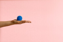 Womans Hand With Spiny Plastic Blue Massage Ball On Pink Background