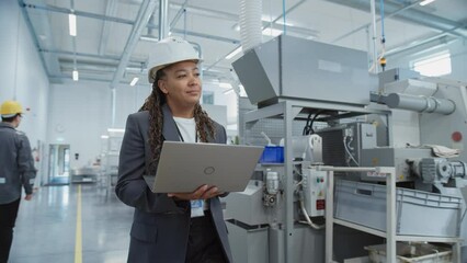 Fototapete - Portrait of a Black Female Engineer in Hard Hat Walking and Using Laptop Computer at Electronic Manufacturing Factory. Technician Working on Daily Tasks and Research and Development Data.