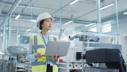 Fototapete - Portrait of an Asian Female Engineer in Hard Hat Standing and Using Laptop Computer at Electronic Manufacturing Factory. Technician Thinking About Daily Tasks and Working on Development Data.