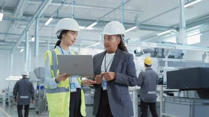 Aufkleber - Two Female Heavy Industry Employees in Hard Hats at Factory. Discussing Job Assignments at Industrial Machine Facility, Using Laptop Computer. Asian Engineer and African American Technician at Work.