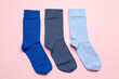 Different blue socks on light pink background, flat lay