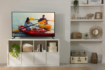 Wall Mural - Modern TV set on wooden stand in room. Scene of adventure movie on screen