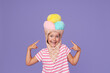 Cute baby girl in an ice cream costume. Funny expression on purple background
