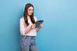 © deagreez - Photo of sweet shiny woman wear striped spectacles reading modern device empty space isolated blue color background