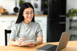 © kucherav - Young Asian freelancer working from home. Happy female student using laptop computer, studying, distance learning. Online education concept