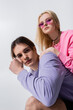 © LIGHTFIELD STUDIOS - Low angle view of young couple in trendy sweatshirts looking at camera isolated on grey.
