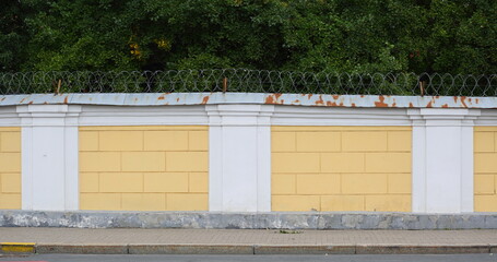 Wall Mural - Yellow-and-white stone fence with barbed wire