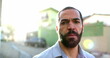 © Marco - Serious hispanic man standing outside in street looking at camera