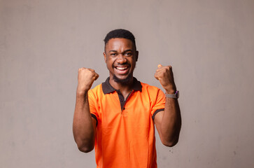 Handsome young Afro-American man employee feeling excited, gesturing actively, keeping fists clenched, exclaiming joyfully with mouth wide opened, happy with good luck or promotion at work