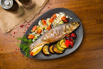 Wall Mural - Fried sea bass with grilled vegetables on black plate