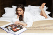© Dragosh - Sensual brunette young woman relaxing on a bed. Young beautiful woman wearing white bathrobe lying on bedroom.