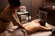 © Dragosh - Back view of a young woman having a back massage treatment. Spa concept.