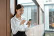 © aksonsat - Business woman working on smartphone in office space.