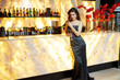 © Dragosh - Full length image of a young brunette woman dressed in elegant grey dress and makeup, posing at the bar with glass of champagne.