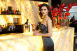 © Dragosh - Portrait of a young woman in grey dress, with hairstyle and makeup, posing at the bar with glass of champagne.