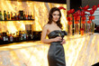© Dragosh - Portrait of a young woman in grey dress, with hairstyle and makeup, posing at the bar with glass of drink.