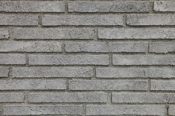 Textured background of the wall is made of gray narrow and long bricks.