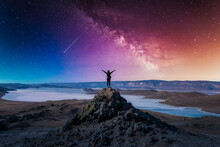 Traveler Woman Raising Arm Standing On Mountain At With Milky Way In Lake Baikal, Siberia, Russia.