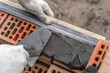 Worker or bricklayer works with trowel laying bricks. Builder makes brickwork on construction site, close up on hands.