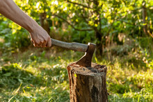 A Man's Hand Holds An Ax Stuck In A Stump