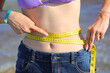 © ChiccoDodiFC - thin girl who measures her waist with the flexible measuring tape and shows her navel