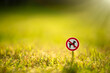 The dog walking sign is prohibited to a round red frame on green grass. It is forbidden to let dogs on the lawn.