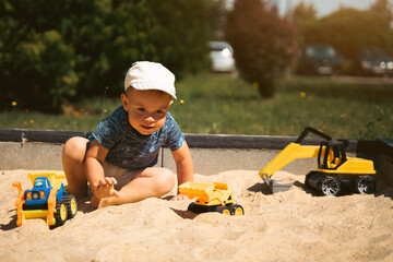 Wall Mural - Child playing in sandbox. Little boy having fun on playground in sandpit. Outdoor creative activities for kids. Summer and childhood concept