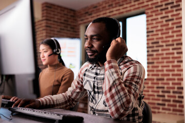 Wall Mural - Male call center receptionist talking to clients on helpline, giving telemarketing assistance to people at customer care service. Helpdesk support consultant working at network reception.