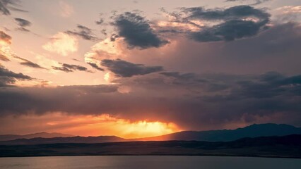 Wall Mural - Timelapse of sunset glowing in the sky as storm rolls in at dusk overlooking Utah Lake during summer monsoon.