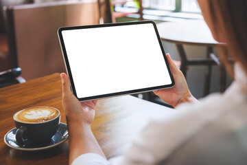 Mockup image of a woman holding digital tablet with blank white desktop screen in cafe