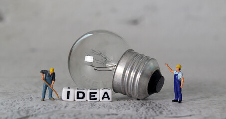 Light bulb and miniature people with business concept. White cube with the word 'IDEA'.
