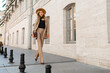 © Svetlana Sokolova - Stunning blond woman in casual leather suit walking on the street in Paris. Outdoor fashion style. Beige hat and purse .  Full lenght.