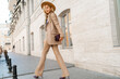 © Svetlana Sokolova - Stunning blond woman in casual leather suit walking on the street in Paris. Outdoor fashion style. Beige hat and purse .  Full lenght.