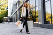 © Svetlana Sokolova - Shopping and fashion concept. Elegant blond woman in casual trendy outfit walking over modern shopping center with  paper bags.  Full lenght.