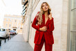 © Svetlana Sokolova - Profeshional fashion model in  elegant red velvet suit posin outdoor in old european city.    Blond wavy hairs, perfet skin, full lips.