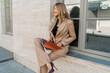 © Svetlana Sokolova - Business woman in stylish beige suit  holdig advertising catalogs and posing outdoor.